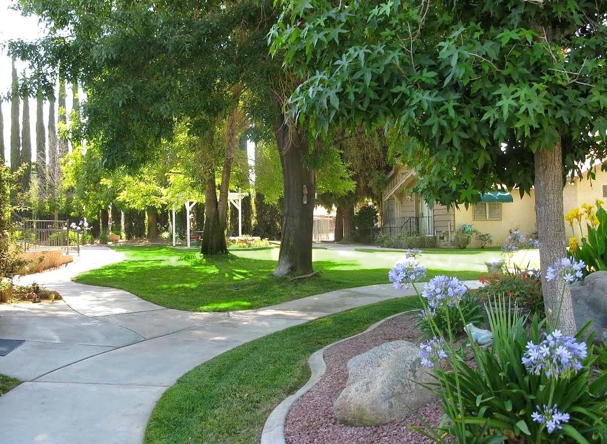 A shaded garden walking path lined with flowers and trees
