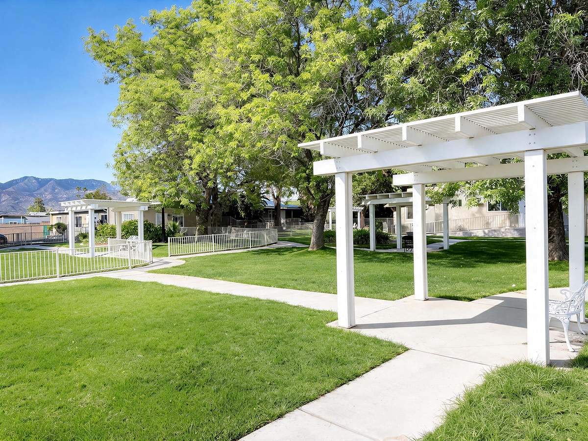 White gazebos on a wide green lawn with walkways and mountain views